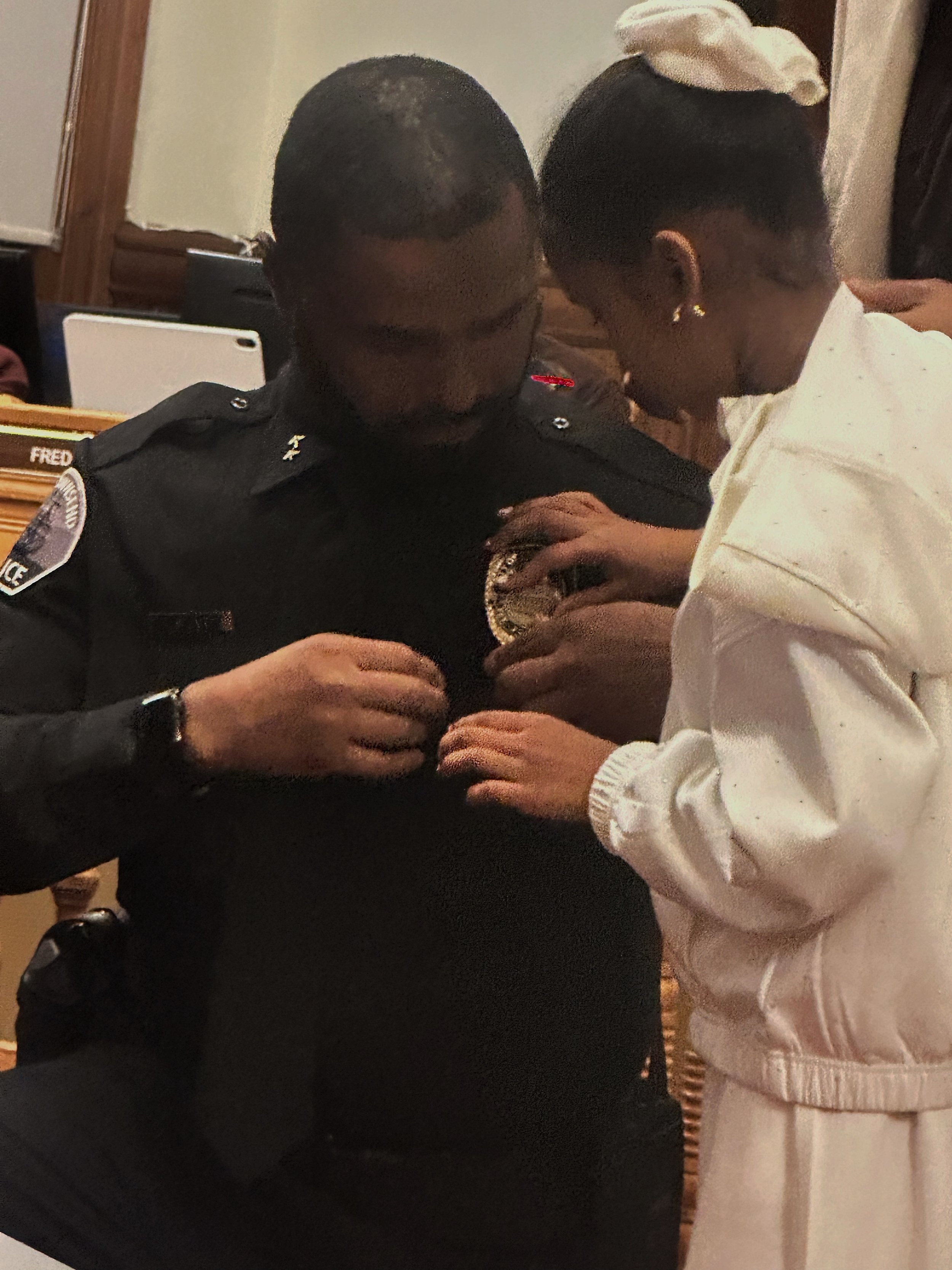   New Deputy Chief of Police Kamal Sharif receives his badge from his daughter. Photo by Rachael Nutting  