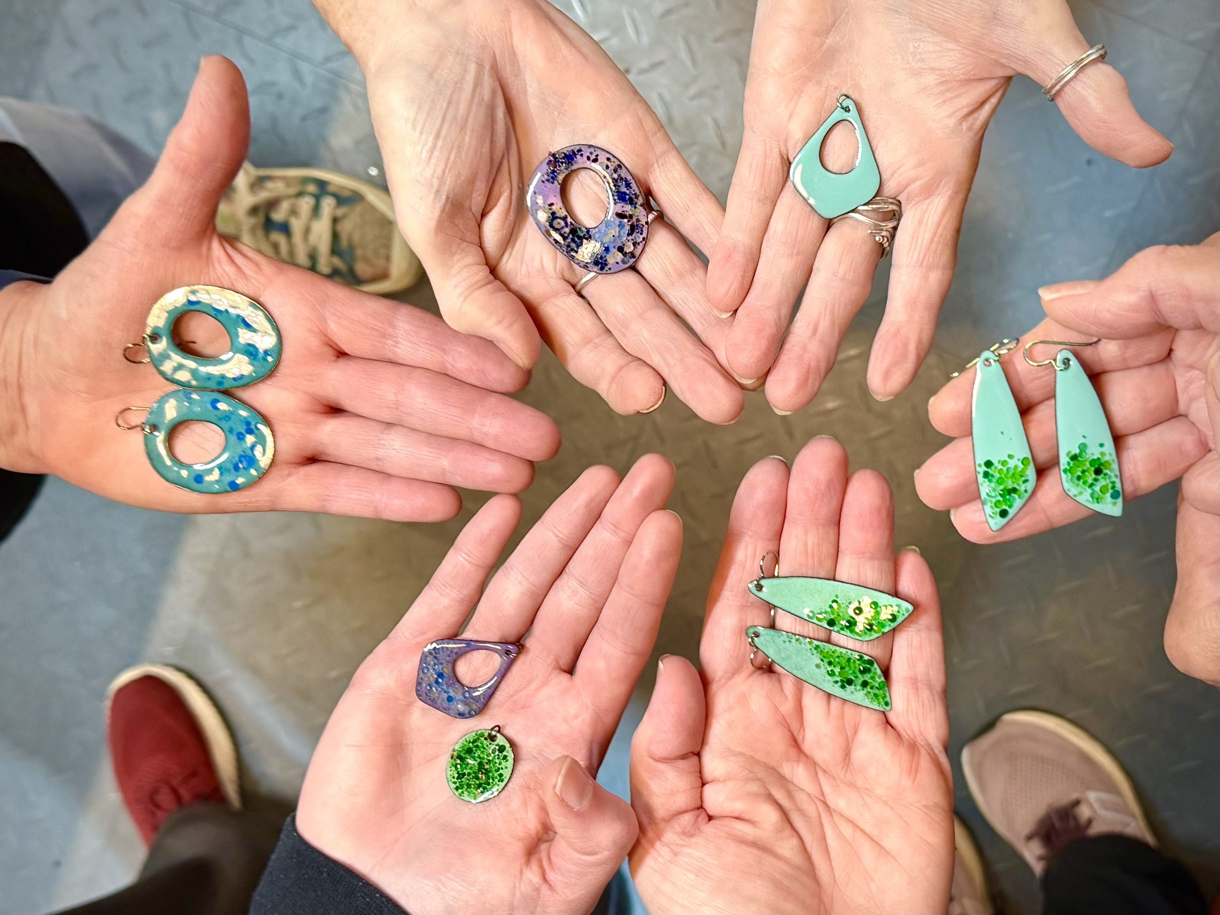 Northwind Art Jewelry Studio students show off the enamel earrings made in a recent Sunday workshop. Photo by Diane Urbani.