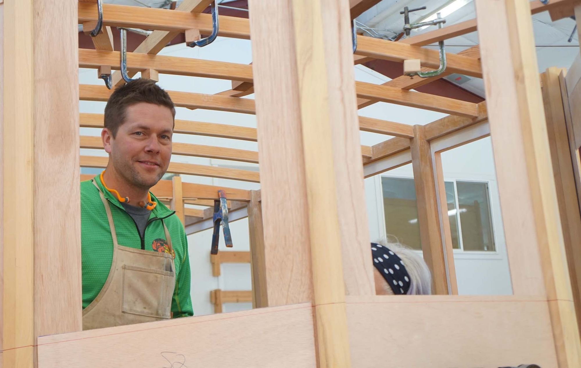 Sean Koomen, a former student of Vice Presidential Candidate Tim Walz, stands within a boat under construction.