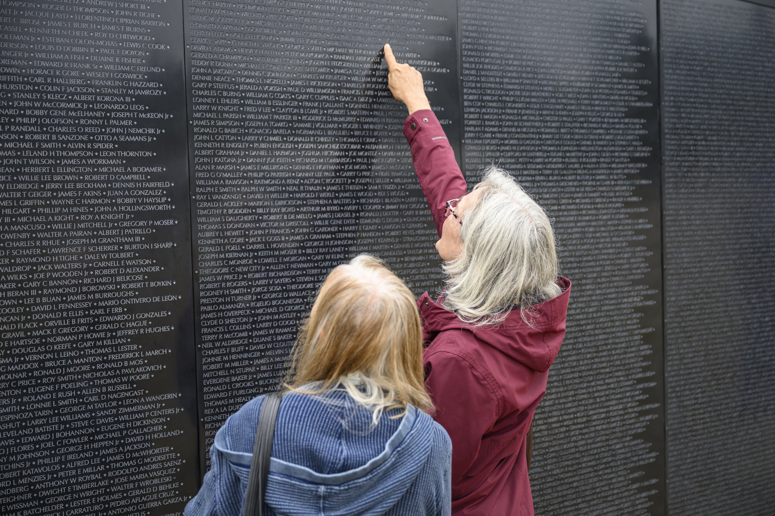   Julie Rohring (left) and Kathleen Raymond look for Daniel I. Nelson's name at The Wall That Heals, a three-quarter scale traveling replica of the Vietnam War Memorial in Washington, D.C. Nelson was the fiancé of Rohring's neighbor. Rohring's husband, Terry S. Rohring, served in Vietnam from 1967 to 1968 as a mechanic in the United States Air Force. Photo by Heather Johnson  