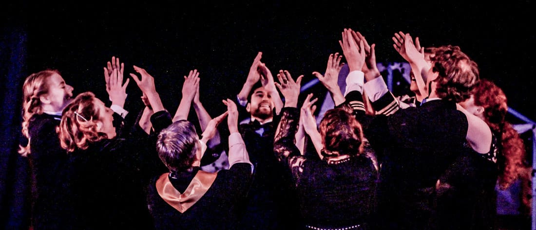 Actors encircled with their hands in the air