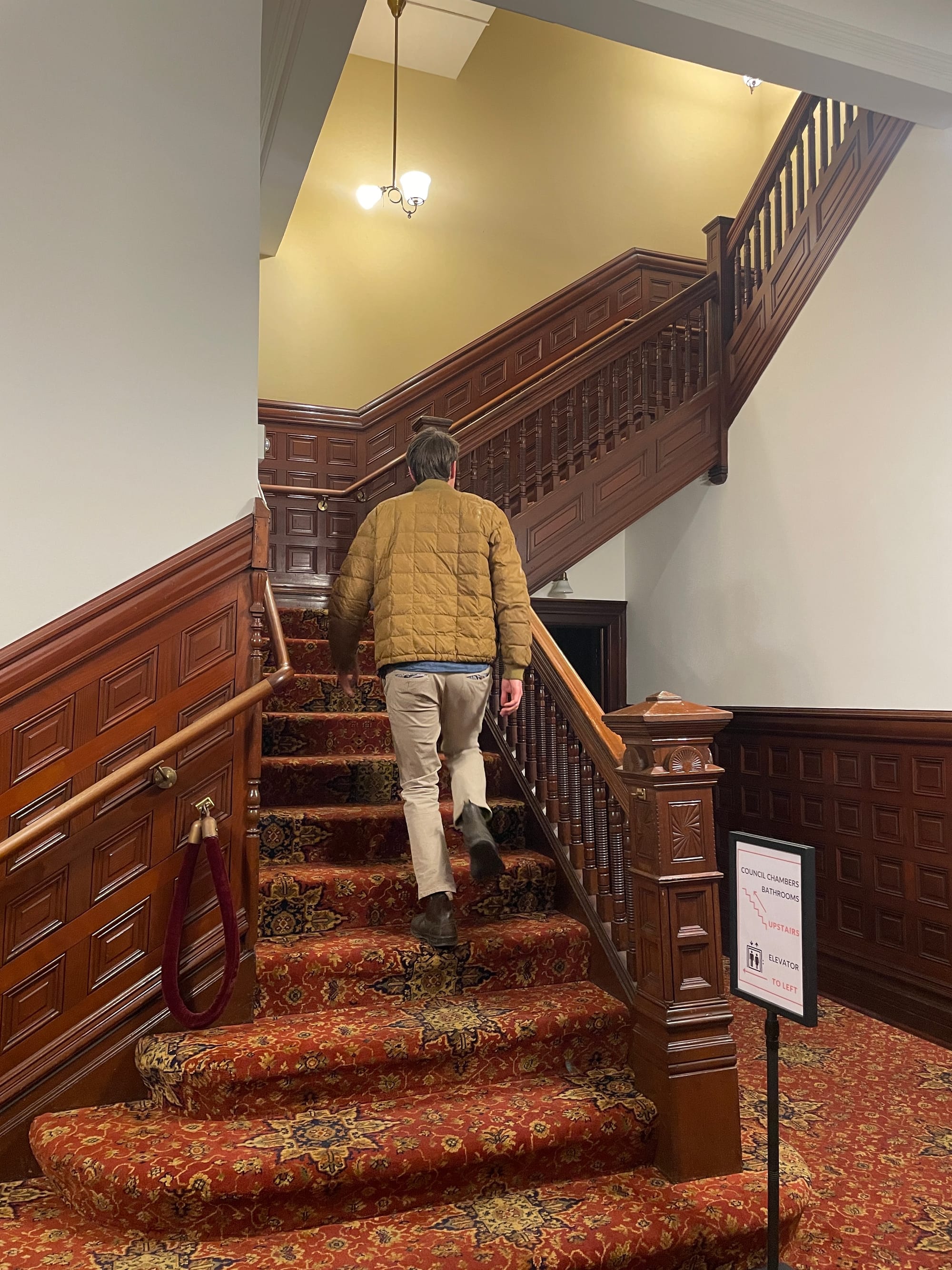  Kellen Lynch walking up the red carpeted stairway to the City Council Chambers.
